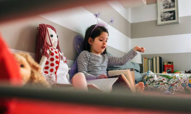 istock Girl disguised reading a book to her doll 948482952