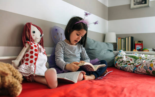 istock Girl disguised reading a book to her doll 948485108