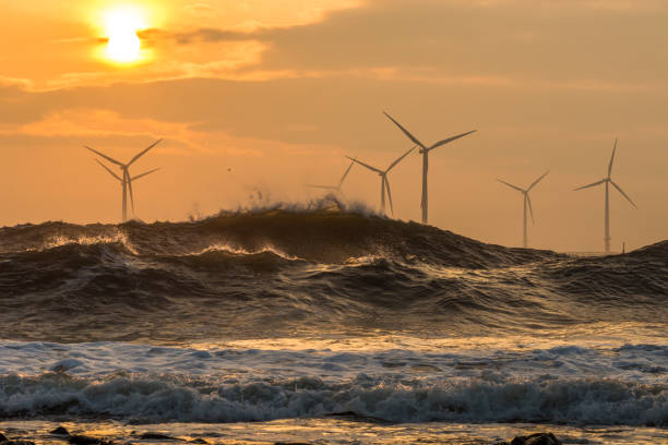 Wave breaking at the beach on a sunny day with wind turbines in background. Photographed in South Western Australia.