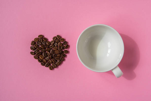istock Coffee beans shaped hearts and white cup on a pink background. Love coffee concept 948494776