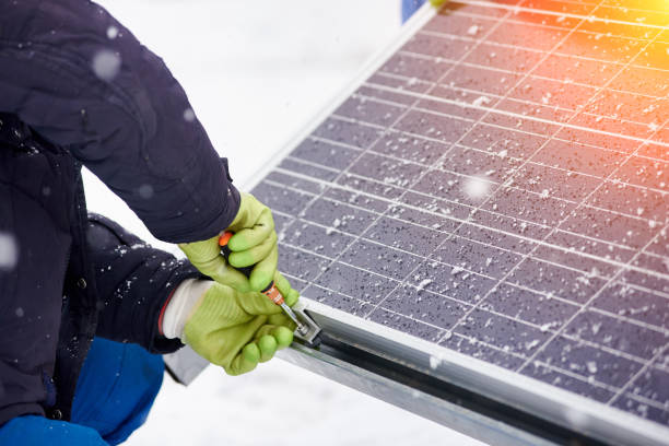 istock Hands of worker installing solar panels in snowy weather. Close-up 948497576