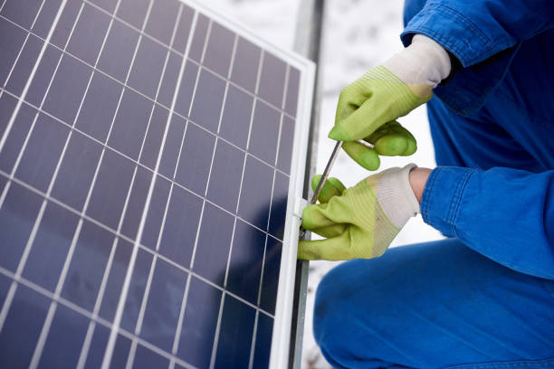 istock Male technician in blue suit installing photovoltaic blue solar modules with screw 948498044