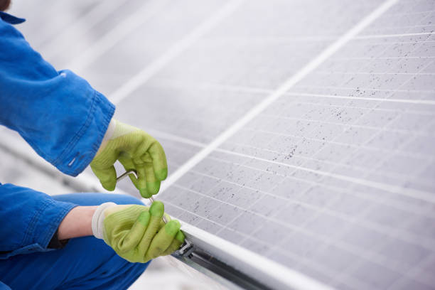 istock Male technician in blue suit installing photovoltaic blue solar modules with screw 948498056
