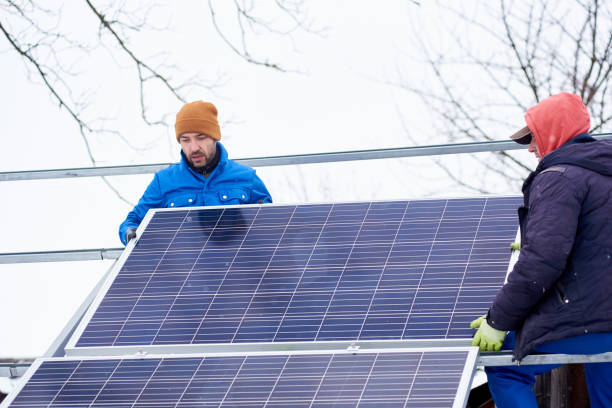 istock Two workers in process of installation of solar battery. Winter 948498060