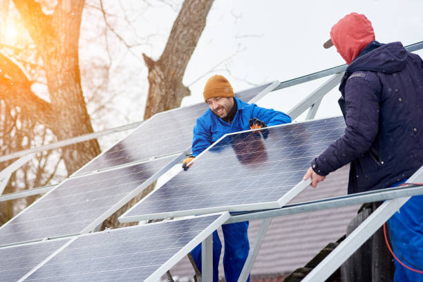 istock Smiling technicians mounting blue solar modules on roof of modern house as a sustainable source of alternative energy. 948498108