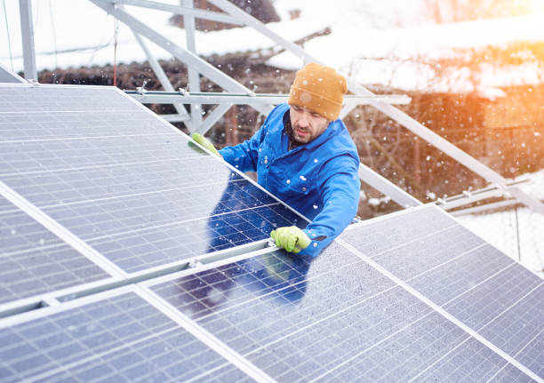 istock Strong male technician in blue suit installing photovoltaic blue solar modules as renewable energy source. 948498144