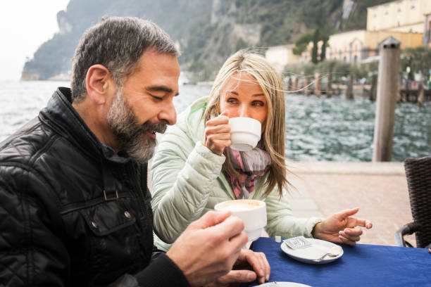 istock Mature couple drinking coffee at lake shore 948499326