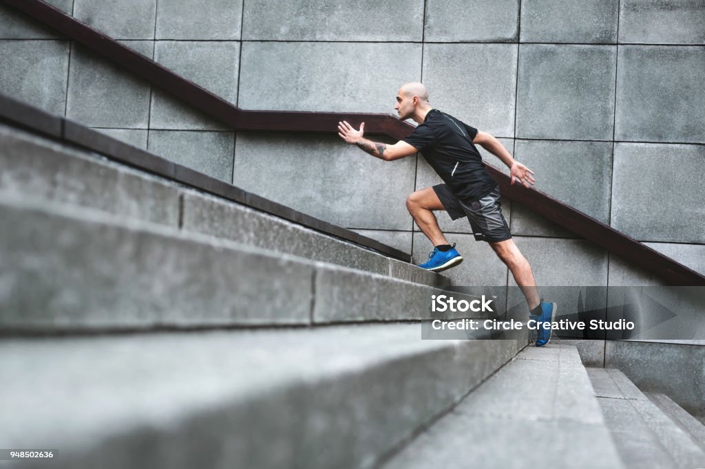 Determination Focussed runner man jogging on stairs Running Stock Photo