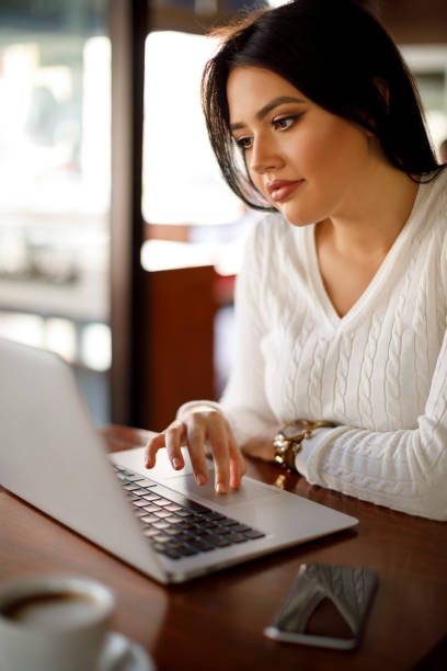 istock Young woman working on laptop at a cafe 948511128
