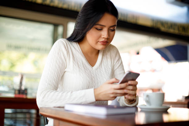 istock Young woman using mobile phone in a coffee shop 948511672