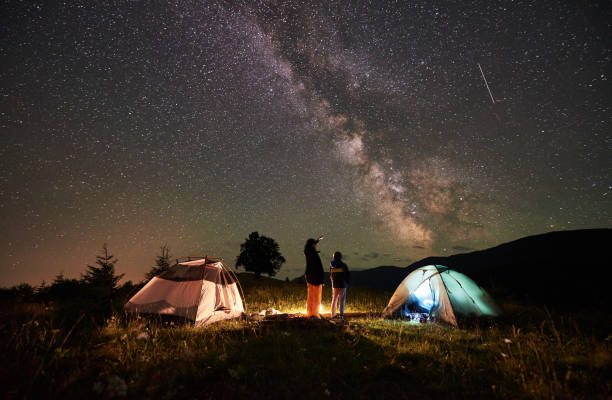 夜の満天の星と天の川で山でキャンプで休んで母と息子の観光客 - キャンプする ストックフォトと画像