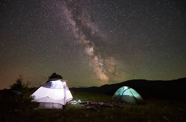 istock Two illuminated tents at night under starry sky with Milky way 948512470