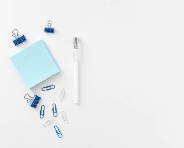 Office table with pen, note papers and paper clips top view