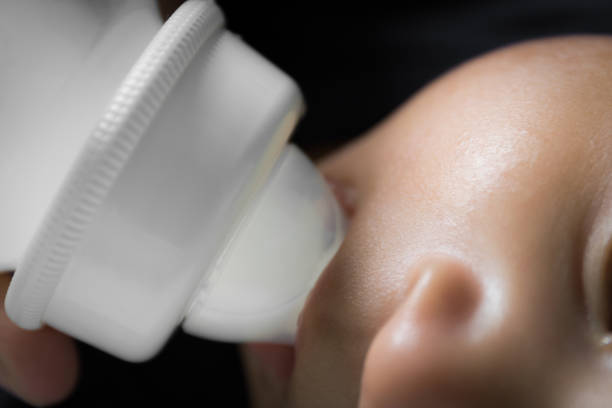 istock close up baby drinking milk from bottle. 948512798