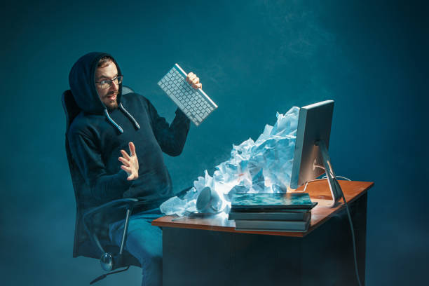 istock Young stressed handsome businessman working at desk in modern office shouting at laptop screen and being angry about spam 948516020