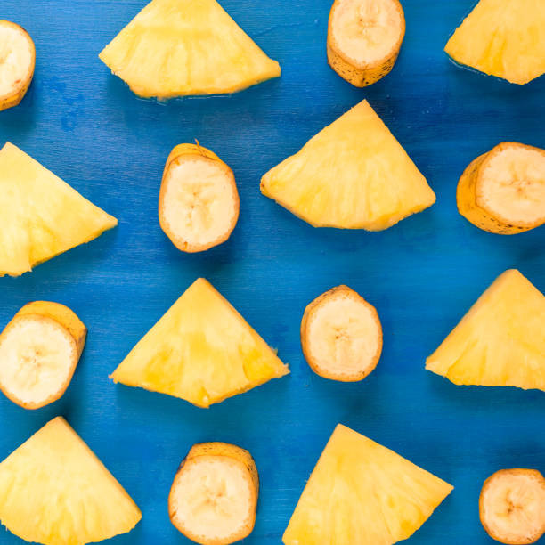 istock banana, pineapple pattern sliced banana slices on blue, top view 948516650