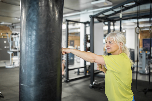 Portrait of senior woman enjoying training on punching bag