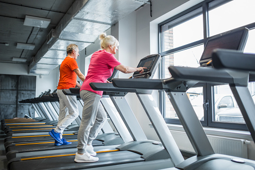 Portrait of senior people walking on treadmill at gym