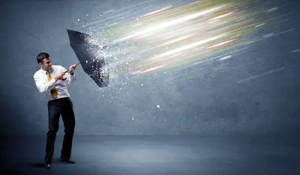 Photo of Business man defending light beams with umbrella concept