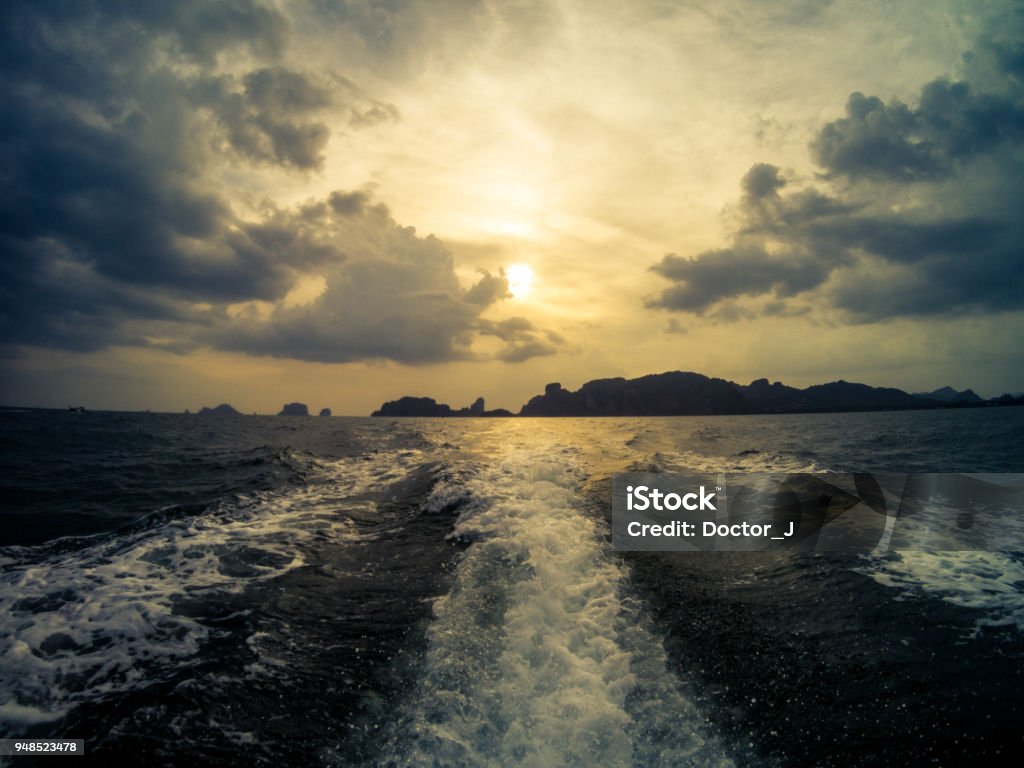 Sunset from a long tail boat. Railay beach on the background. Krabi, Thailand. View of the sunset from a long tail boat. Railay beach on the background. Krabi, Thailand. Andaman Sea Stock Photo