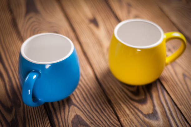 istock Two colored empty ceramic clean mugs on old worn brown wooden table 948524022
