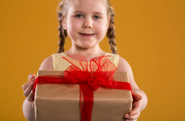 istock Young happy girl holding present with red ribbon 948524416