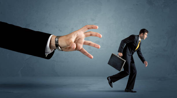istock Business man running away from a huge hand concept 948535856