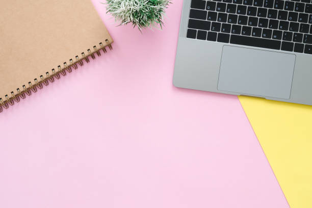istock Creative flat lay photo of workspace desk. Top view office desk with laptop and blank empty notebooks on pastel pink yellow color background. Top view with copy space, flat lay photography. 948543564