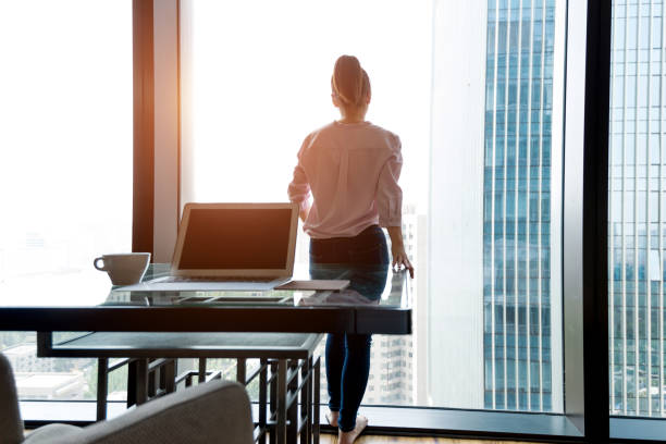 istock Woman standing and looking out the window 948545014