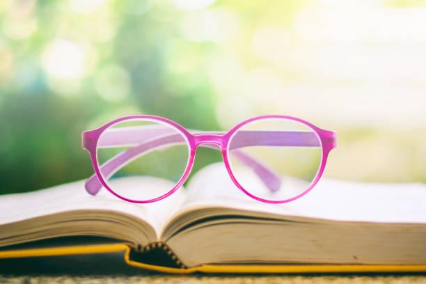 istock Eyeglasses placed on an opened book against blurred natural green background 948545116