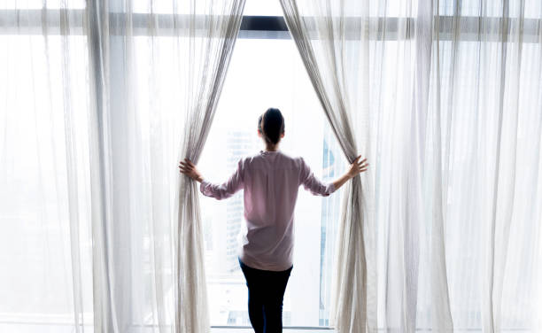 istock Woman opening curtains and looking out 948545770