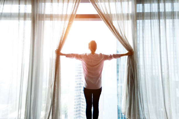 istock Woman opening curtains and looking out 948547902