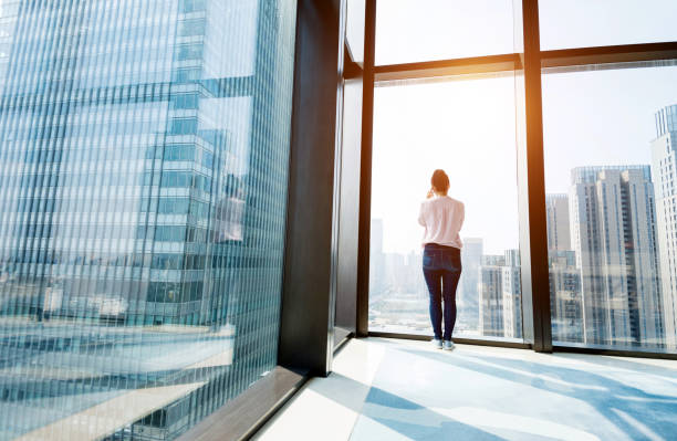 istock Woman standing by the window and using phone 948547908