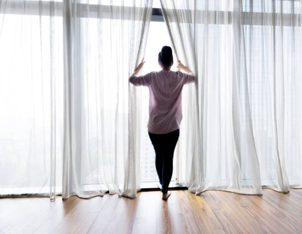 istock Woman opening curtains and looking out 948548680