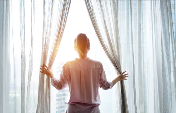istock Woman opening curtains and looking out 948550128