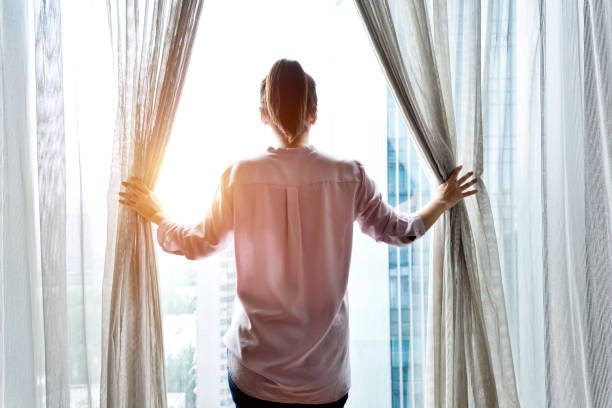 istock Woman opening curtains and looking out 948550330