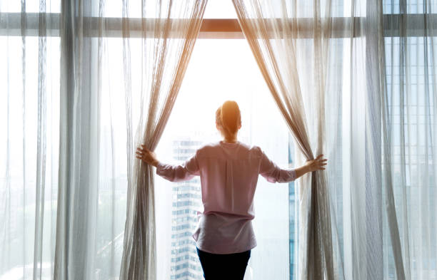 istock Woman opening curtains and looking out 948550334