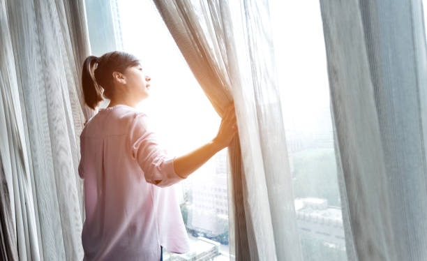 istock Woman opening curtains and looking out 948550592