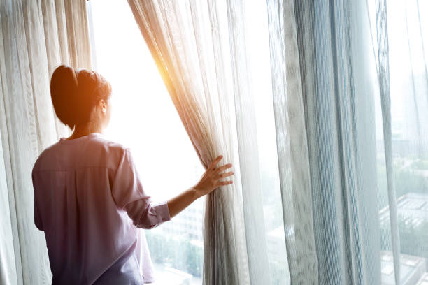 istock Woman opening curtains and looking out 948550824