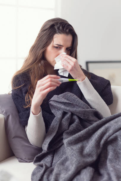 istock Woman measuring her temperature with a thermometer 948559396