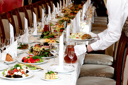 waiter serving food at luxury table set at wedding reception, catering in restaurant