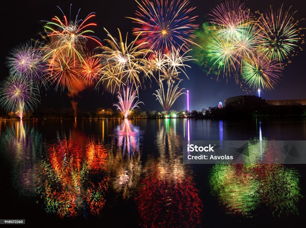 Multiple fireworks with reflections over lake Dutzendteich at spring fair in Nuremberg Firework Display Stock Photo