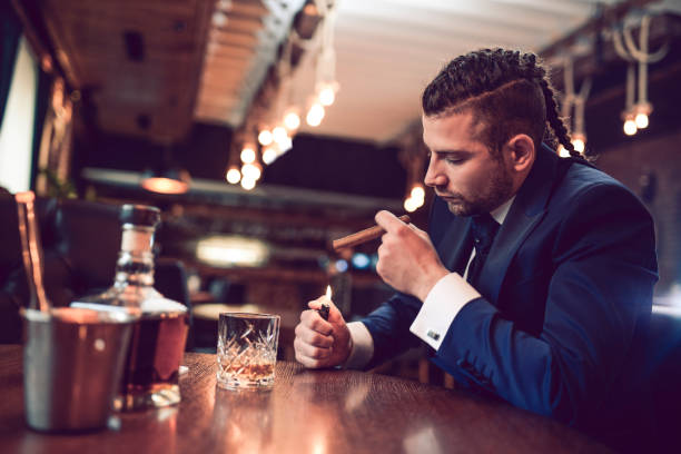 istock Businessman Lighting up a Cigar and Drinking Whisky in Restaurant 948575742