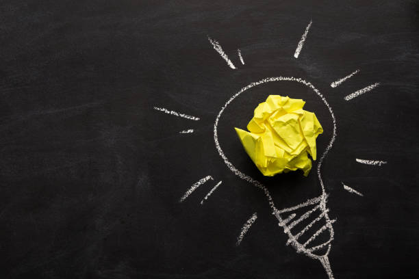 istock Electric bulb drawn on chalkboard with yellow paper for glowing light 948576880