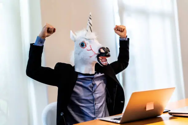Photo of Business man with Unicorn Mask Celebrating