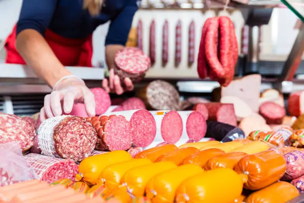 Butcher shop woman holding meat and sausage in her hand