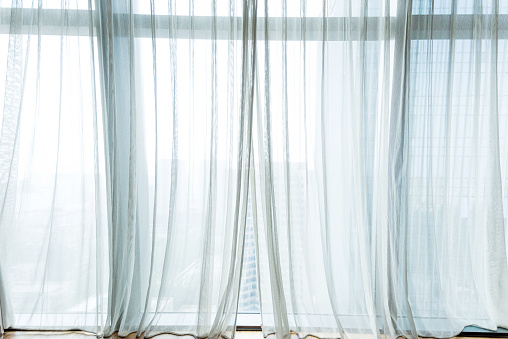 White curtain with golden rod hanging in the window, background with copy space, full frame horizontal composition