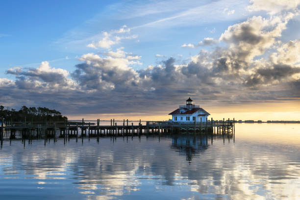 Roanoke Marshes Lighthouse at Sunrise with Dramatic Sky Roanoke Marshes Lighthouse in Manteo, North Carolina with clouds at sunrise reflecting in calm water. cape hatteras stock pictures, royalty-free photos & images