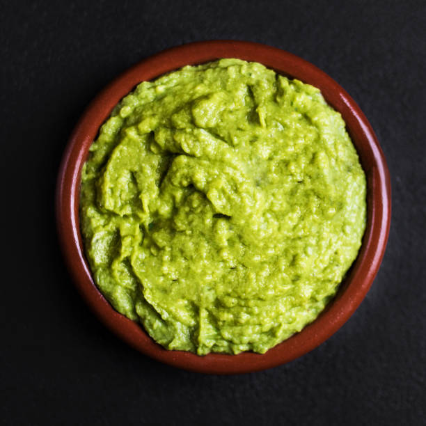 istock Guacamole spread  in clay bowl on a black background. Avocado sauce. Top view with copy space