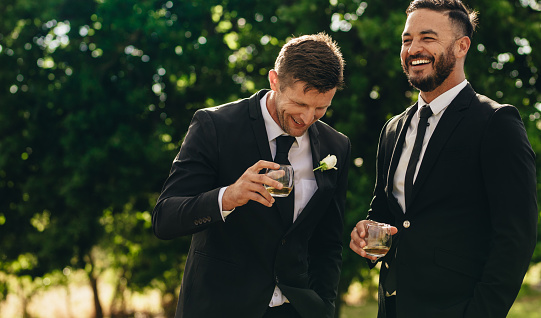 Novio y mejor a hombre bebiendo en la fiesta de boda photo